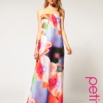 Woman in a pastel floral petite maxi dress standing on steps with relaxed posture.